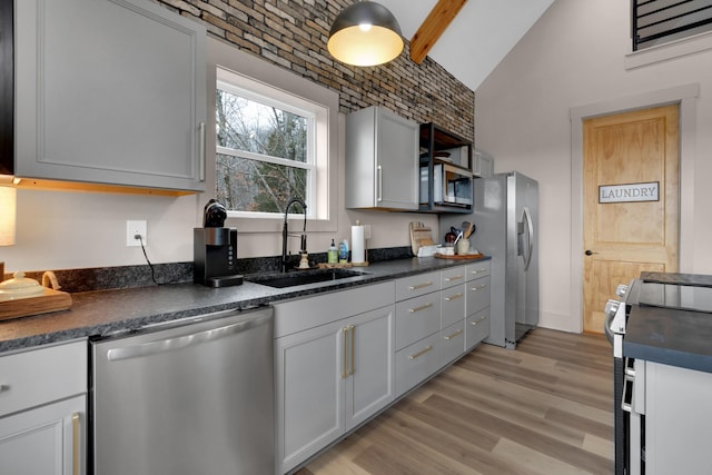 kitchen featuring brick ceiling, lofted ceiling, sink, stainless steel appliances, and light wood-type flooring