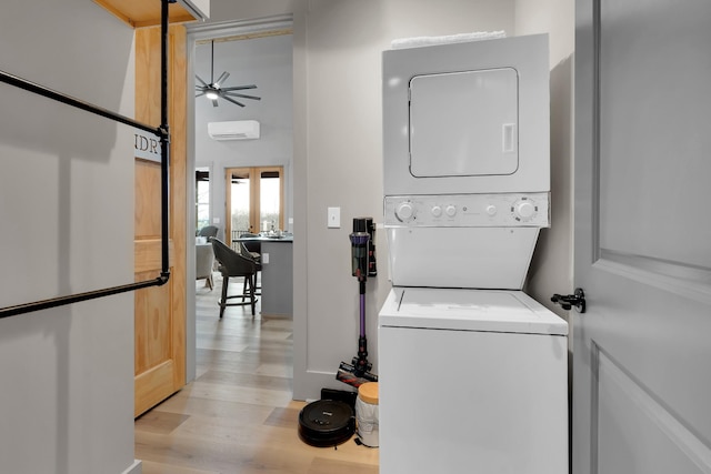 laundry area featuring a wall mounted air conditioner, light hardwood / wood-style floors, stacked washer and clothes dryer, and ceiling fan