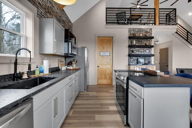 kitchen with sink, white cabinetry, stainless steel appliances, high vaulted ceiling, and light wood-type flooring