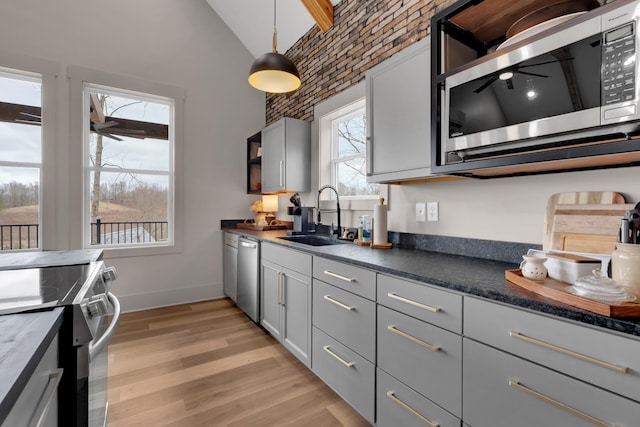 kitchen featuring pendant lighting, sink, gray cabinetry, light hardwood / wood-style floors, and stainless steel appliances