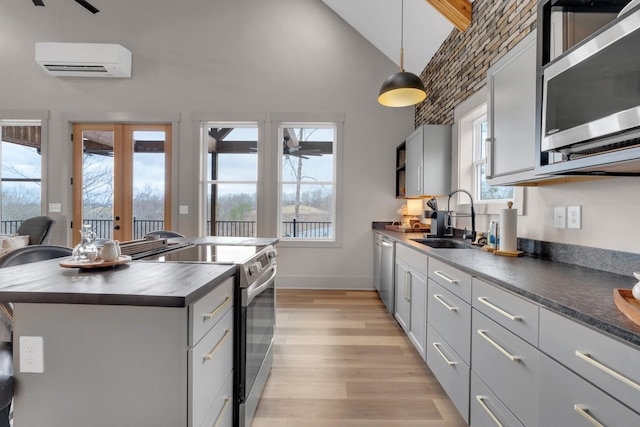 kitchen with sink, hanging light fixtures, an AC wall unit, a kitchen island, and stainless steel appliances