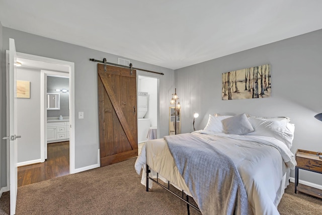 bedroom featuring connected bathroom, a barn door, and dark carpet