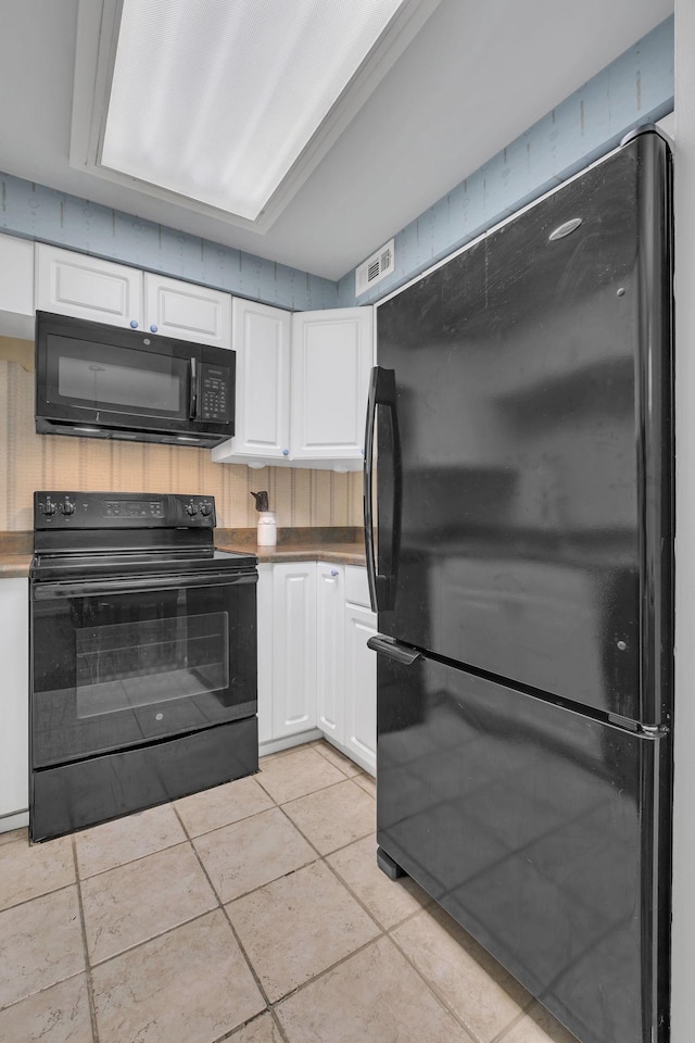 kitchen featuring white cabinets, light tile patterned floors, and black appliances