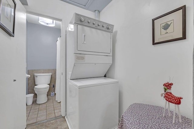 washroom with stacked washer and clothes dryer and tile walls