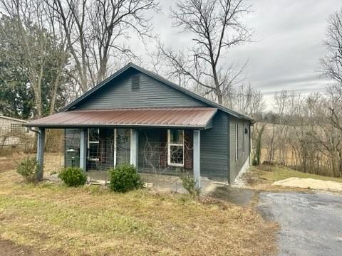 view of front of home featuring covered porch, driveway, and metal roof