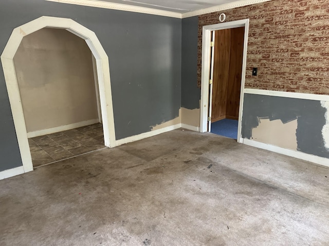 empty room with dark carpet, ornamental molding, and brick wall