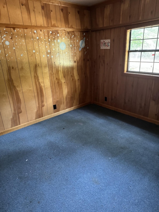 carpeted spare room featuring wood walls