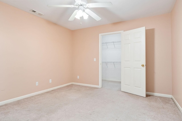 unfurnished bedroom with ceiling fan, light colored carpet, a closet, and a walk in closet