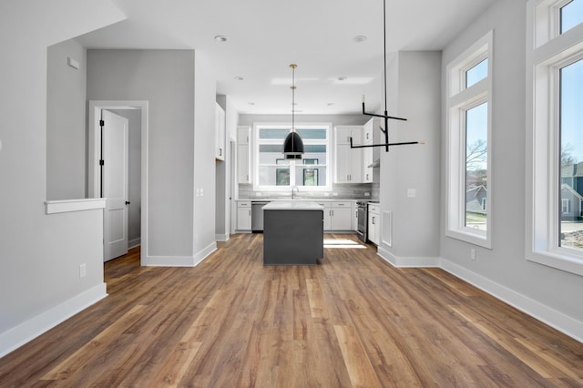 kitchen featuring sink, white cabinetry, a center island, tasteful backsplash, and decorative light fixtures