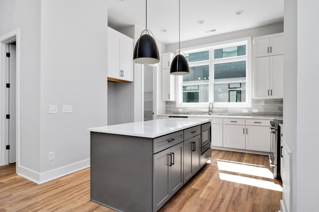 kitchen featuring gray cabinets, white cabinetry, light hardwood / wood-style floors, a kitchen island, and decorative light fixtures