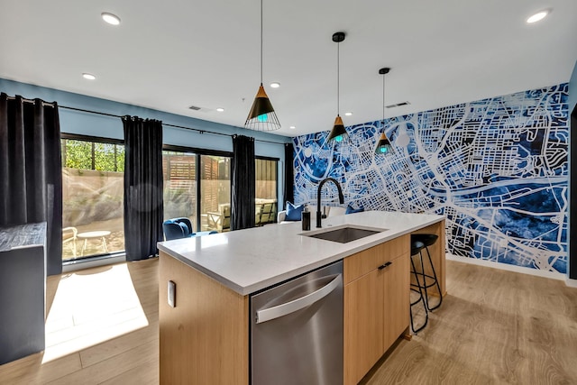 kitchen featuring decorative light fixtures, sink, a kitchen island with sink, stainless steel dishwasher, and light hardwood / wood-style floors