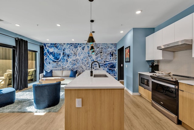 kitchen with stainless steel electric stove, white cabinetry, sink, hanging light fixtures, and a center island with sink