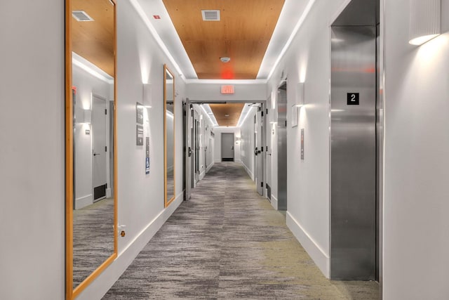 hallway with elevator and a raised ceiling