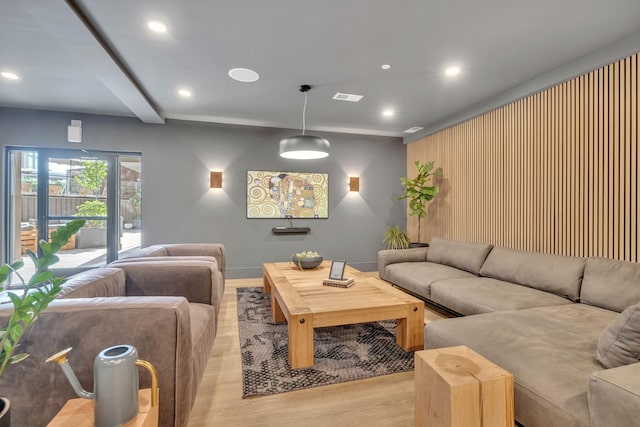 living room featuring beamed ceiling and light hardwood / wood-style flooring