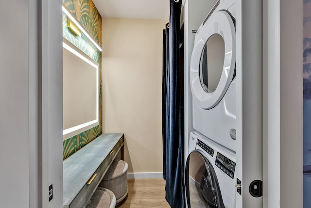 laundry room with stacked washer and dryer and light hardwood / wood-style flooring