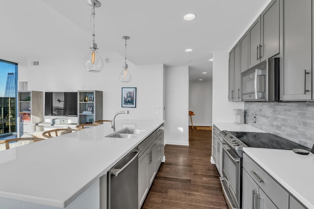 kitchen with stainless steel appliances, sink, a center island with sink, and gray cabinets