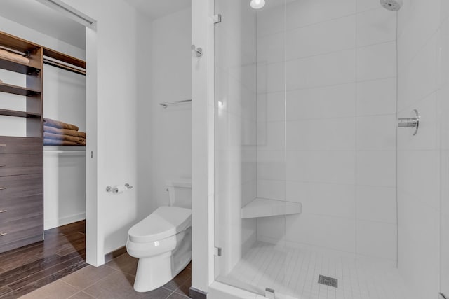 bathroom featuring tile patterned floors, toilet, and a tile shower