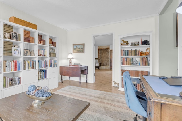 office featuring built in shelves, ornamental molding, and light hardwood / wood-style floors