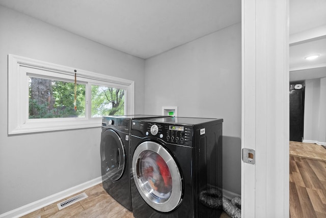 clothes washing area with separate washer and dryer and hardwood / wood-style floors