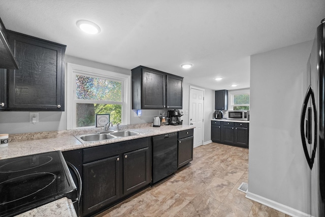 kitchen with sink, wall chimney range hood, and black appliances