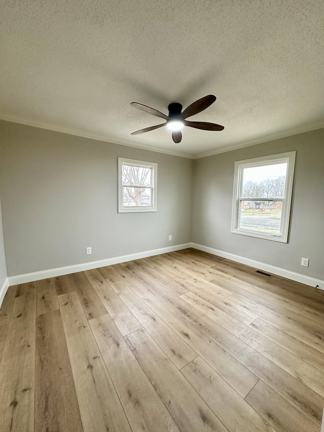 empty room with ceiling fan, ornamental molding, light hardwood / wood-style floors, and a textured ceiling