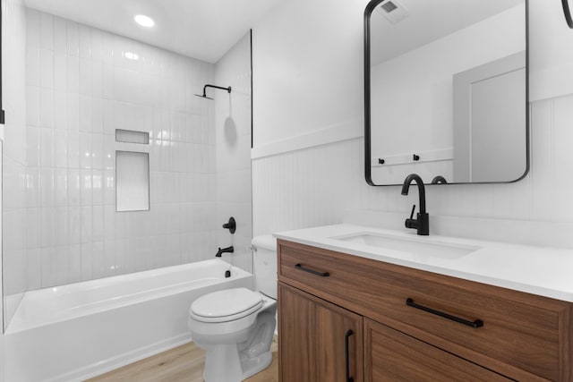 full bathroom with tiled shower / bath combo, vanity, wood-type flooring, and toilet