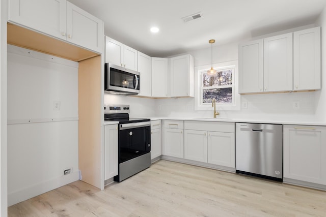 kitchen featuring white cabinetry, stainless steel appliances, sink, and hanging light fixtures