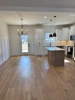 kitchen featuring stove, a center island, pendant lighting, and white cabinets