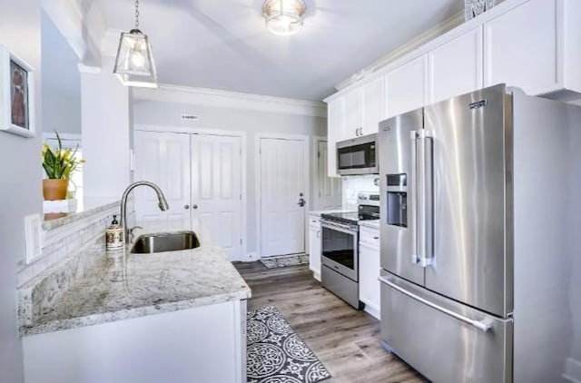 kitchen with white cabinetry, sink, light stone counters, and appliances with stainless steel finishes