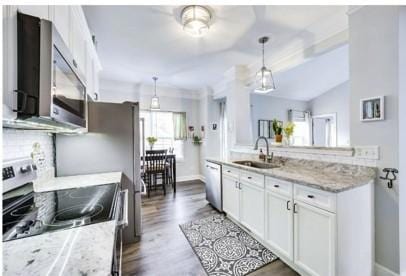 kitchen featuring appliances with stainless steel finishes, pendant lighting, white cabinetry, sink, and light stone countertops