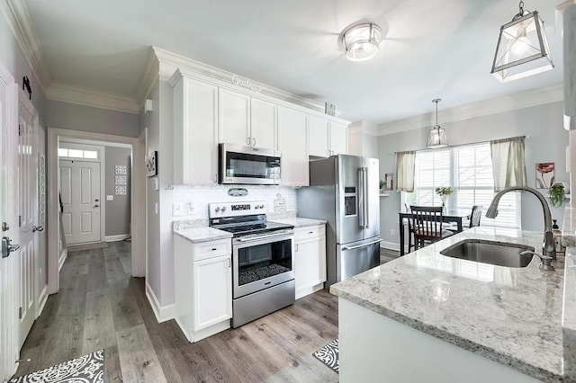 kitchen with pendant lighting, stainless steel appliances, sink, and white cabinets