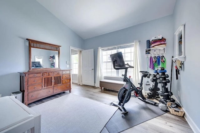 workout room with vaulted ceiling and light wood-type flooring