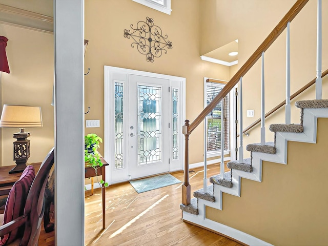 entrance foyer with a towering ceiling and light hardwood / wood-style floors