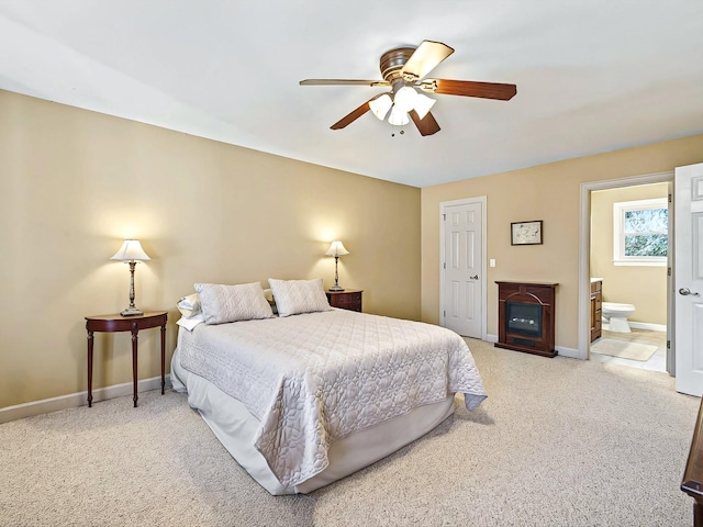 bedroom featuring light carpet, ensuite bath, a fireplace, and ceiling fan