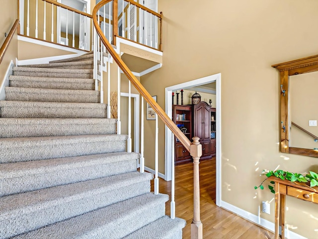 stairway with hardwood / wood-style flooring and a high ceiling