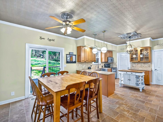 dining area with ornamental molding, sink, and ceiling fan with notable chandelier