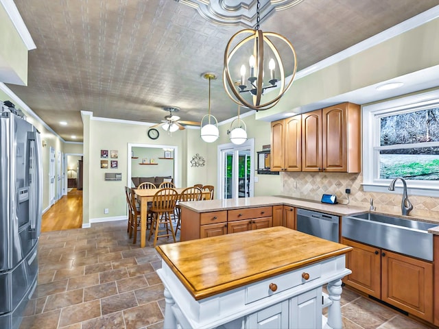 kitchen featuring pendant lighting, stainless steel appliances, crown molding, and sink