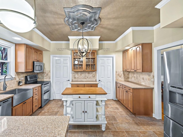 kitchen featuring butcher block countertops, crown molding, stainless steel appliances, and sink