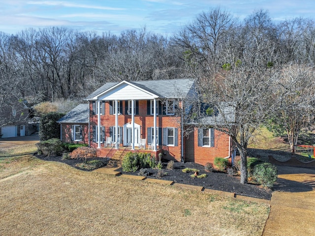 greek revival house with a front yard and covered porch