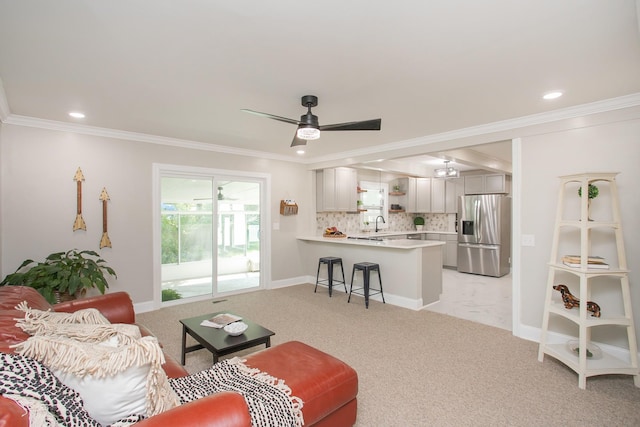 carpeted living room featuring crown molding, sink, and ceiling fan