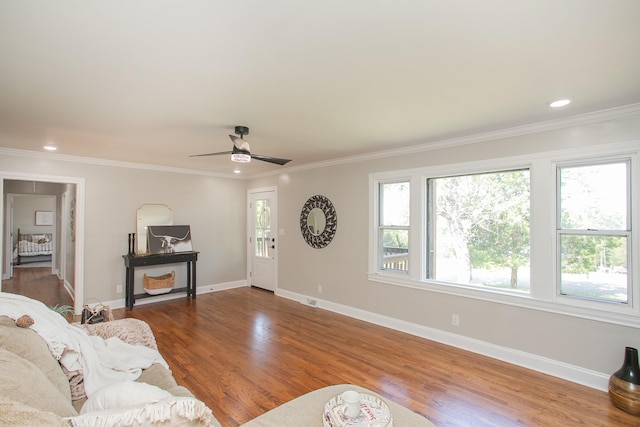 living area with crown molding, wood finished floors, and baseboards