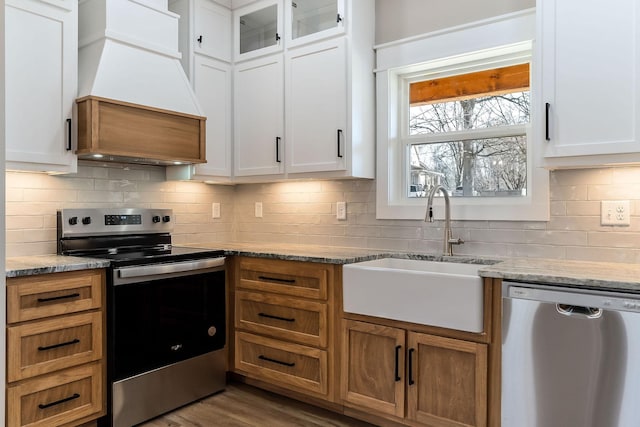 kitchen with sink, stainless steel appliances, white cabinets, and premium range hood