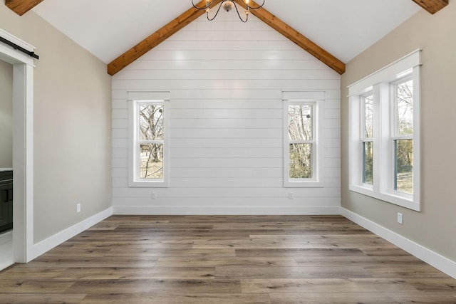 interior space featuring wood-type flooring, a barn door, vaulted ceiling with beams, and a healthy amount of sunlight