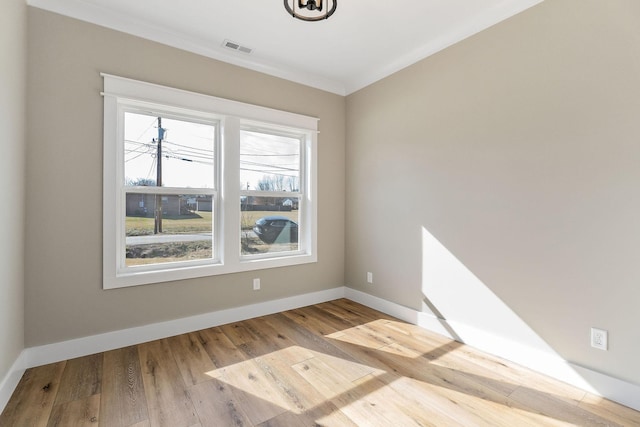 empty room featuring ornamental molding and light wood-type flooring