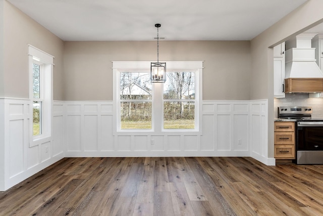 unfurnished dining area featuring plenty of natural light, dark hardwood / wood-style floors, and a notable chandelier