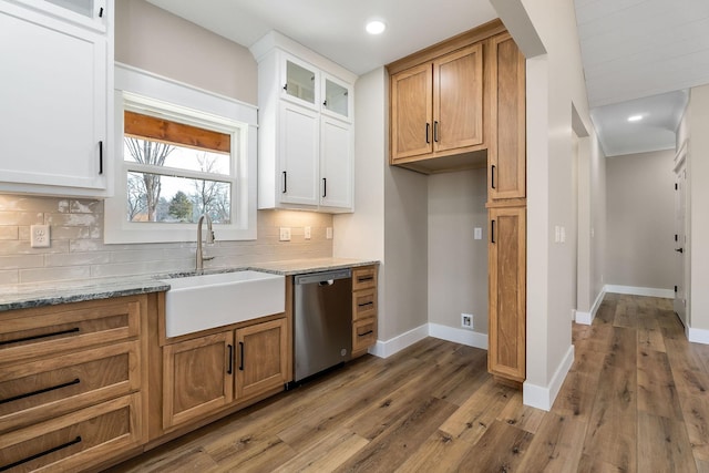 kitchen featuring sink, dishwasher, white cabinetry, light stone countertops, and decorative backsplash