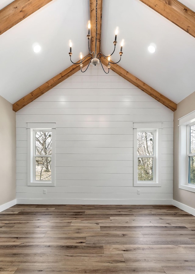 additional living space with wood-type flooring, a chandelier, and lofted ceiling with beams