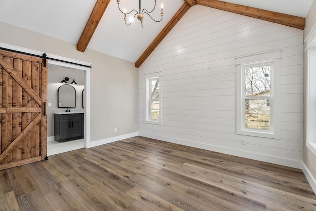 interior space with sink, a chandelier, wood-type flooring, a barn door, and beamed ceiling