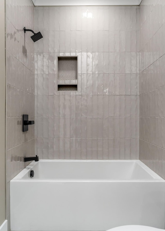 bathroom with tiled shower / bath and toilet