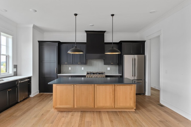 kitchen featuring a center island, light hardwood / wood-style flooring, appliances with stainless steel finishes, wall chimney range hood, and backsplash